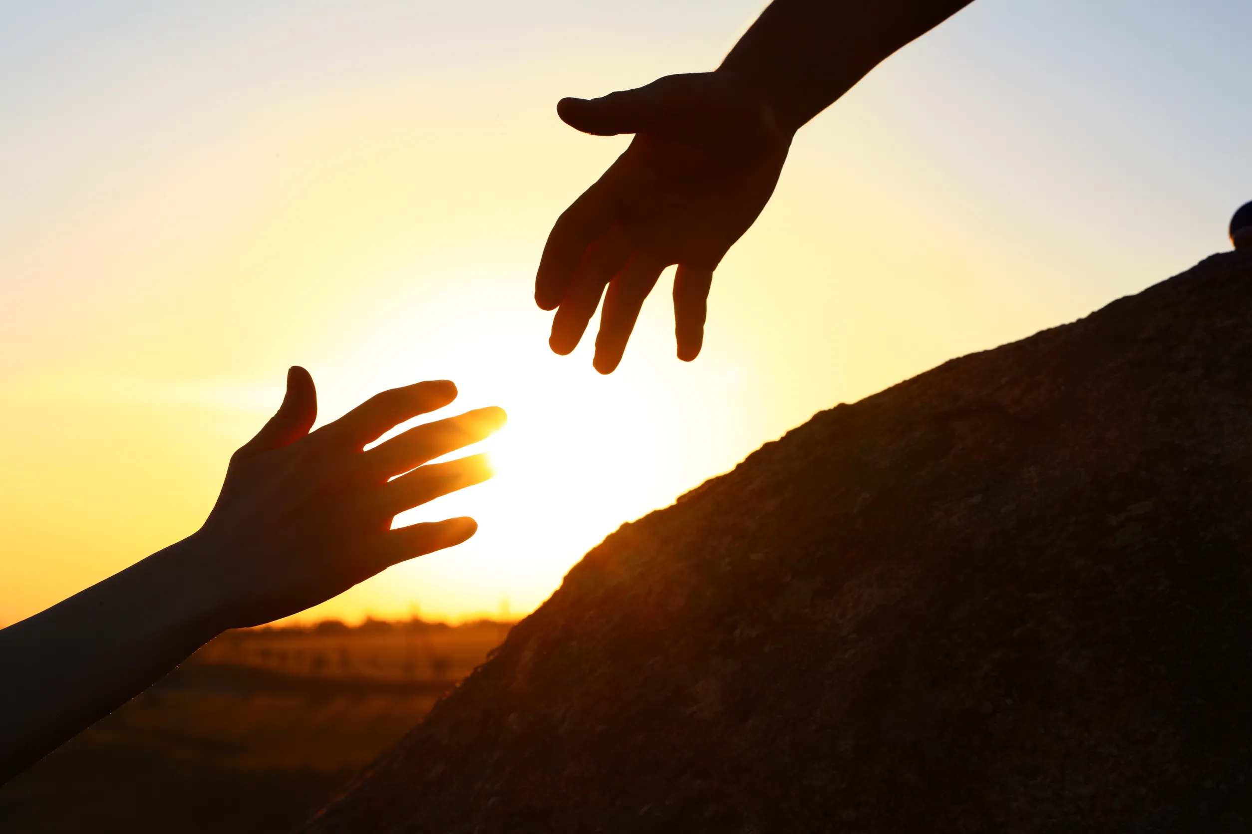 Hiker helping friend outdoors at sunset. Help and support concept