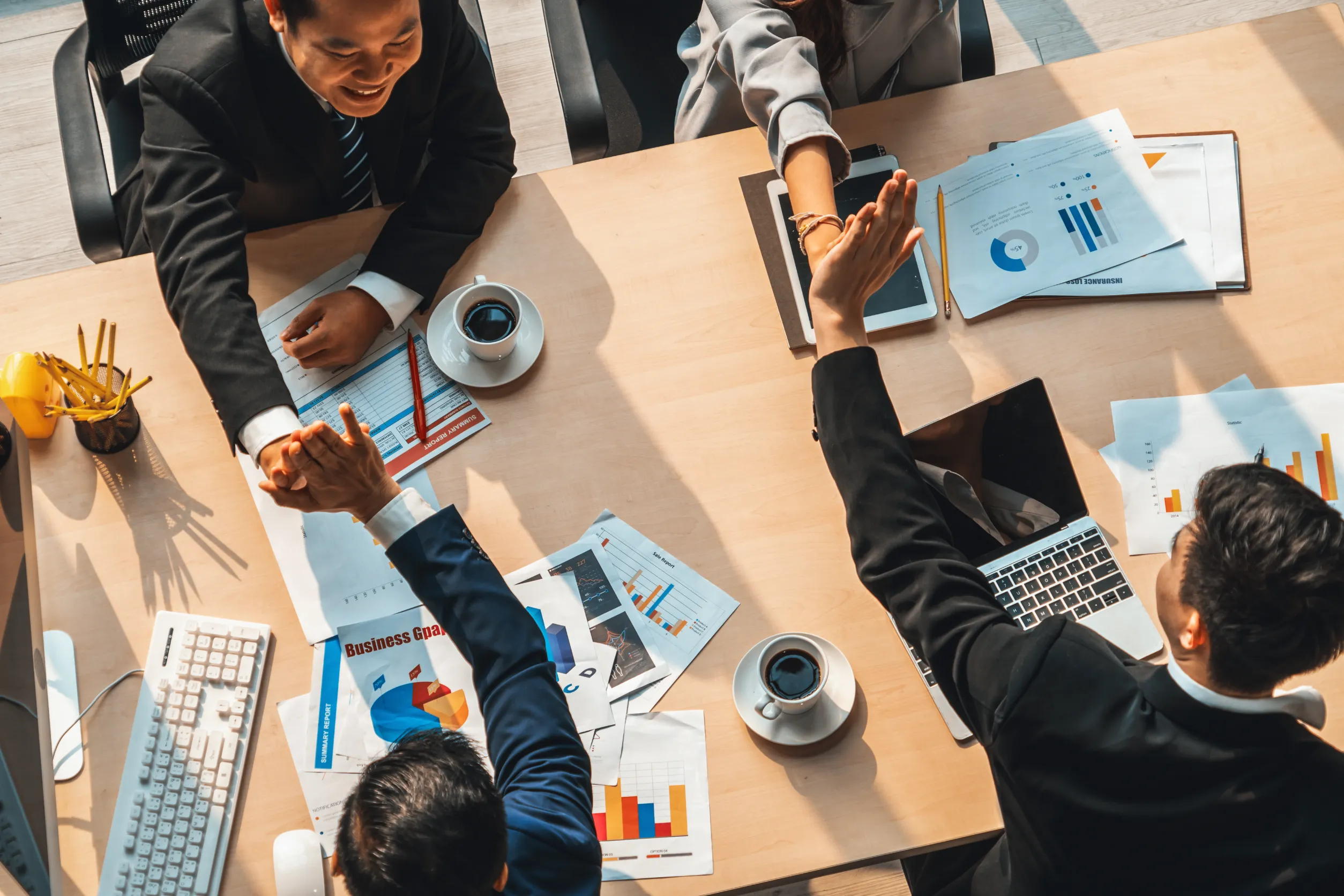 Happy business people celebrate teamwork success together with joy at office table shot from top view . Young businessman and businesswoman workers express cheerful victory show unity support .