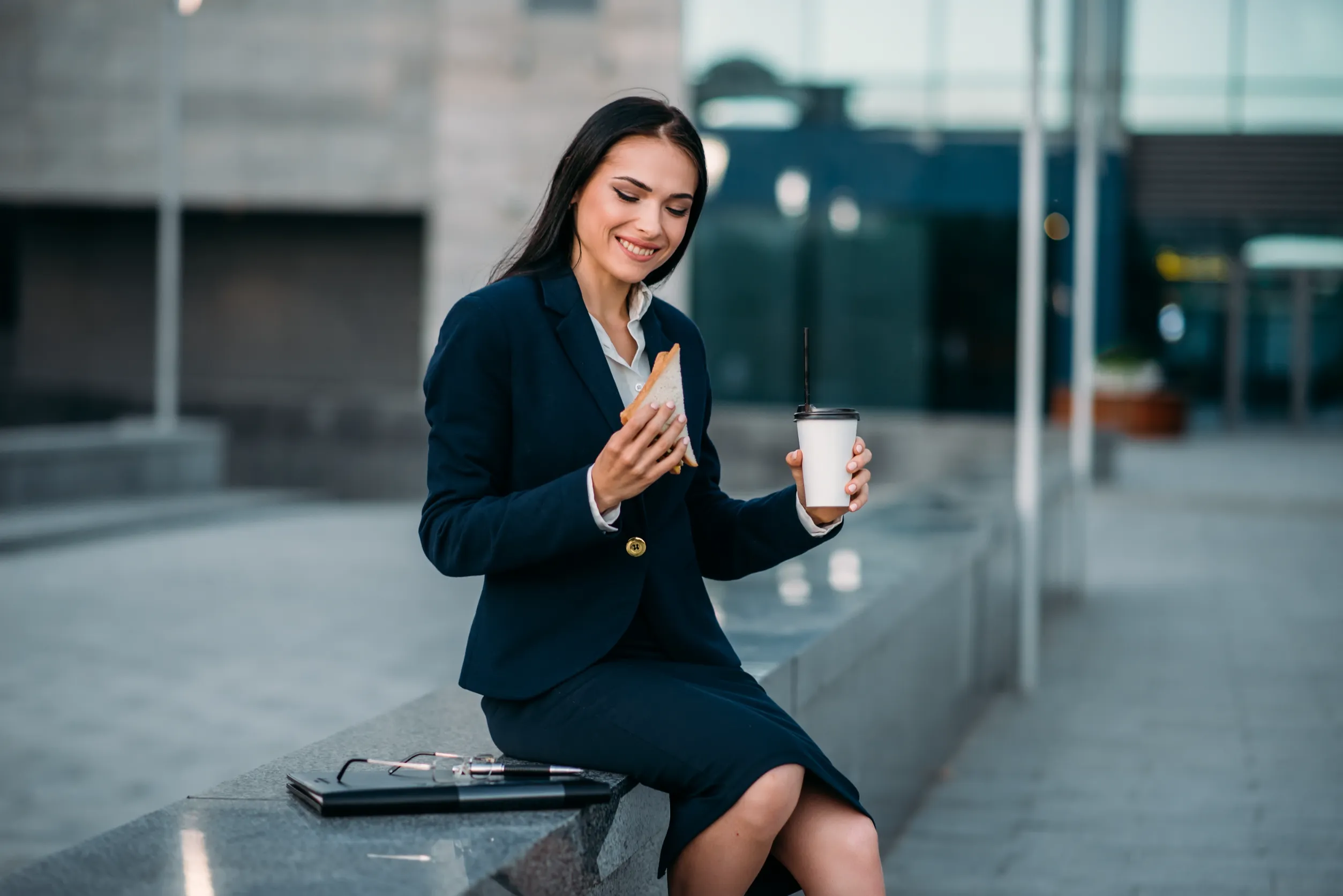 Happy business woman with sandwich and coffee