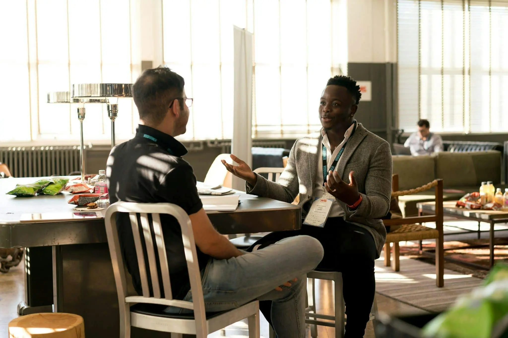 Two men sitting in chairs facing each other discuss business